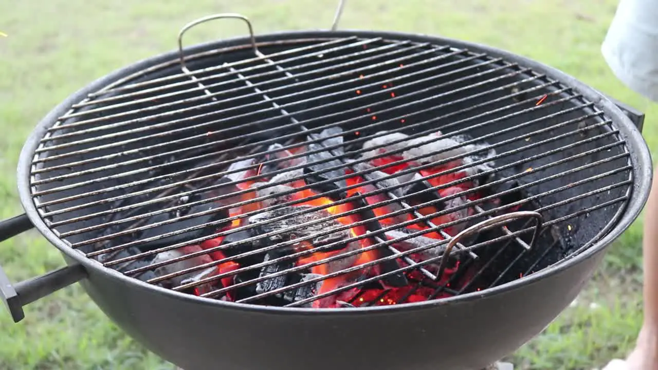 Arranging burning charcoal on a Charcoal BBQ