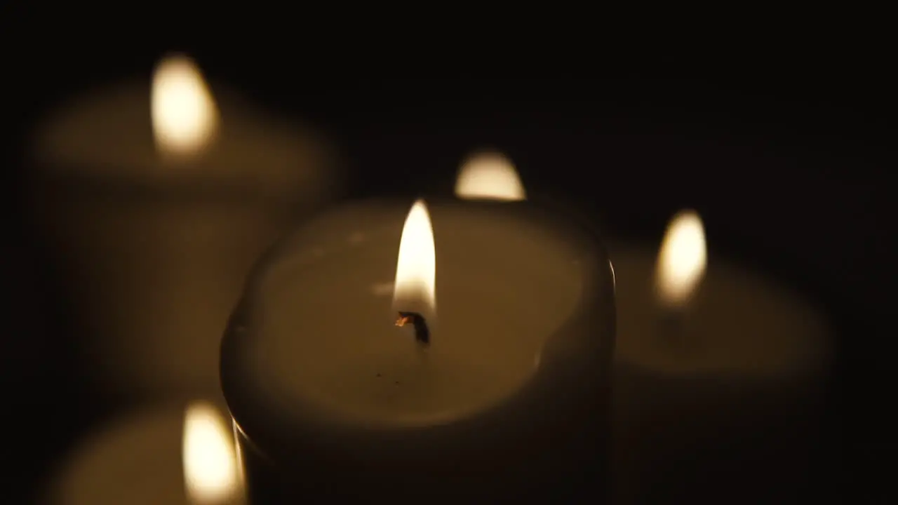 Slow movement over burning candles composition on black background candles of different sizes stand side by side slow motion