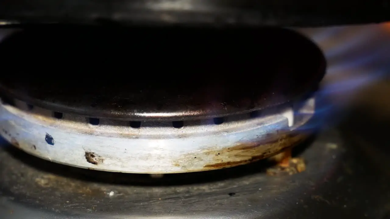 Dirty gas stove or kitchen burner is burning in blue flame