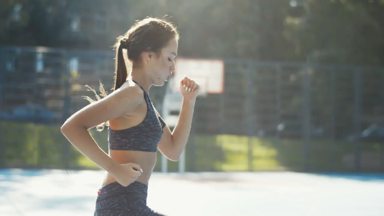 Side View Of A Sporty Woman Running In Place At Outdoor Court On A Summer Day