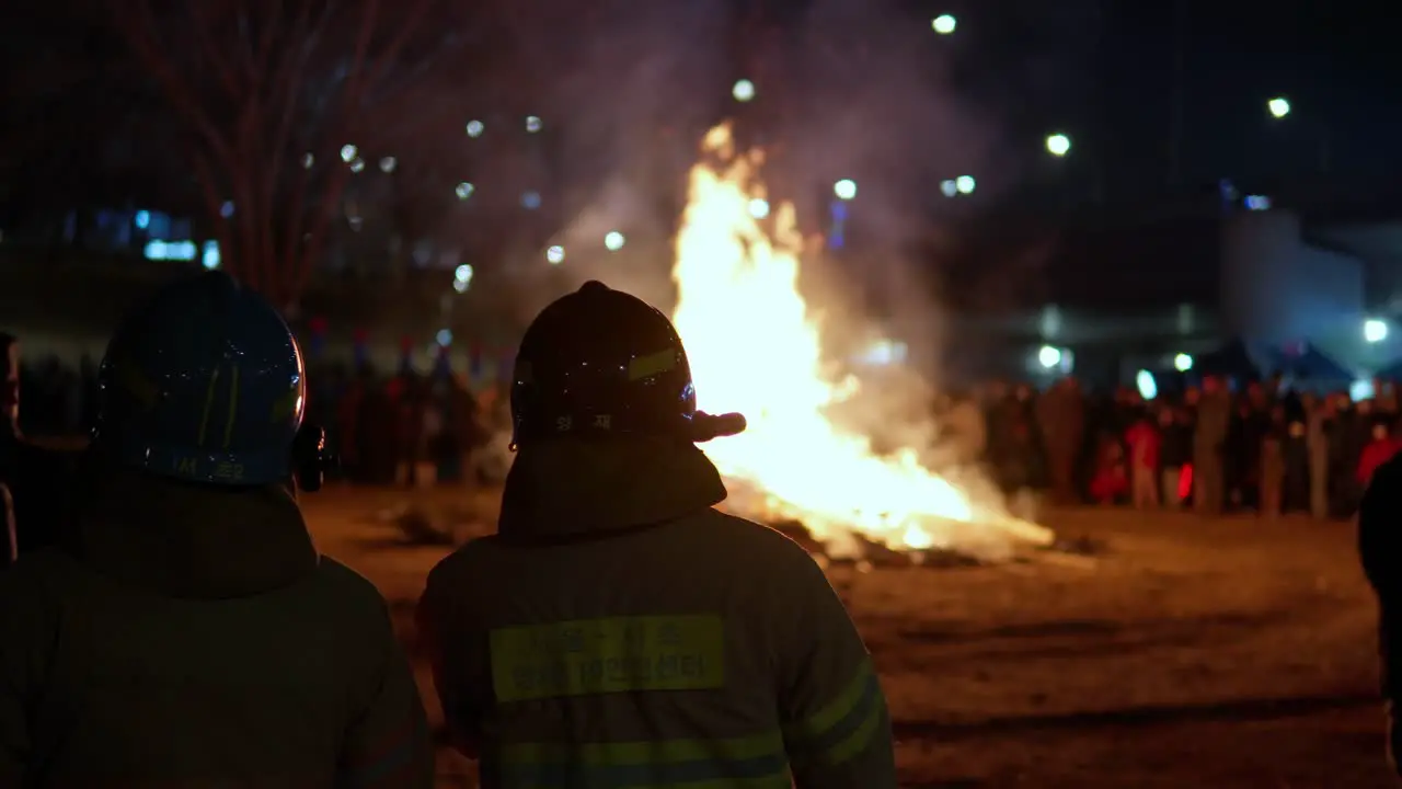 Yangjae District Firemen Standing Near Daljip Burning Fire at Night Seoul at Jeongwol Daeboreum First Full Moon Festival in Gangnam Seoul on February 5 2023 slow motion