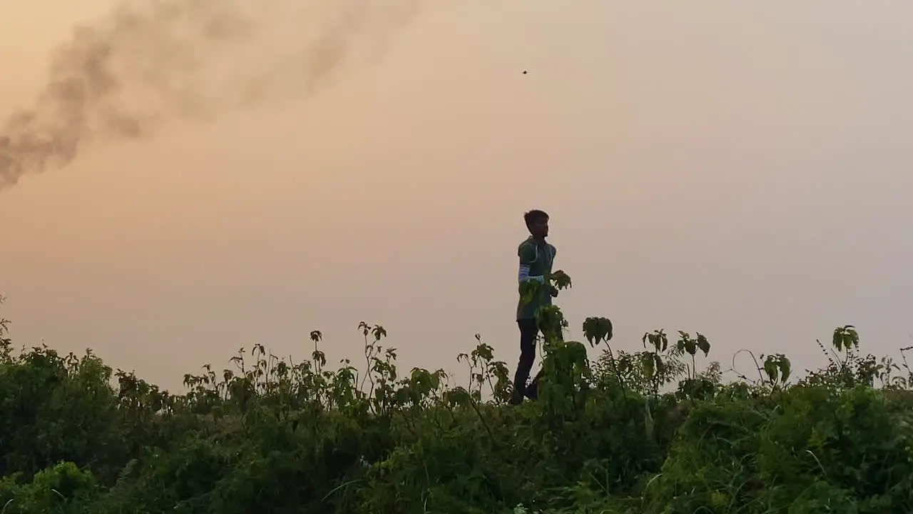 Tracking shot man jogging outside with polluting burning gas plant behind at morning day