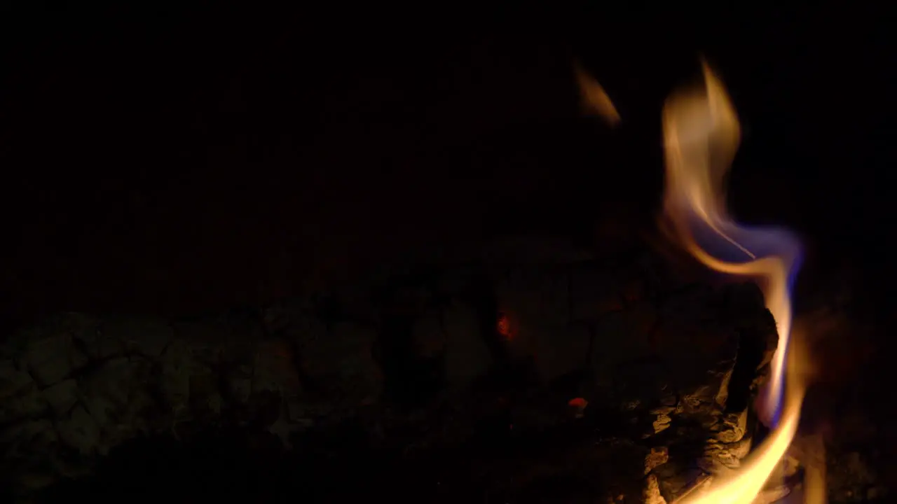 A log burning in a fireplace with yellow flames rising all around it