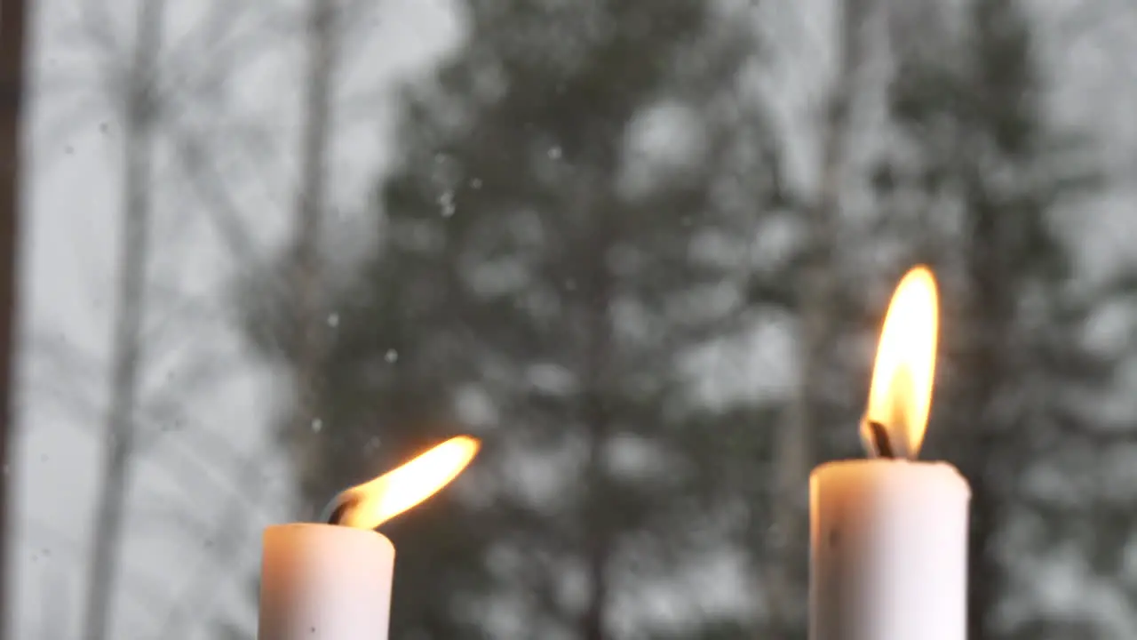 Rack Focus Of winter snow falling to lit candles in window