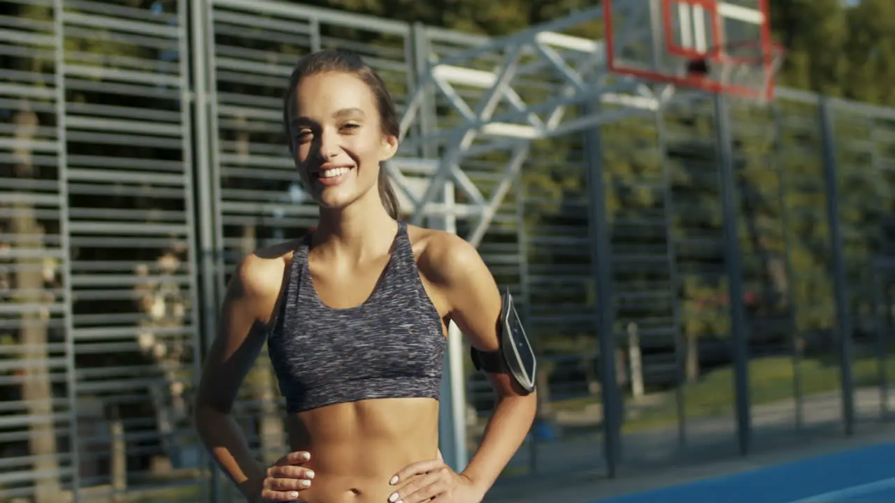 Portrait Of A Sporty Woman Smiling Cheerfully At The Camera While Standing At Sport Court On A Summer Day