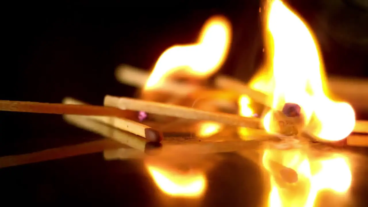 Lit matches falling on black background