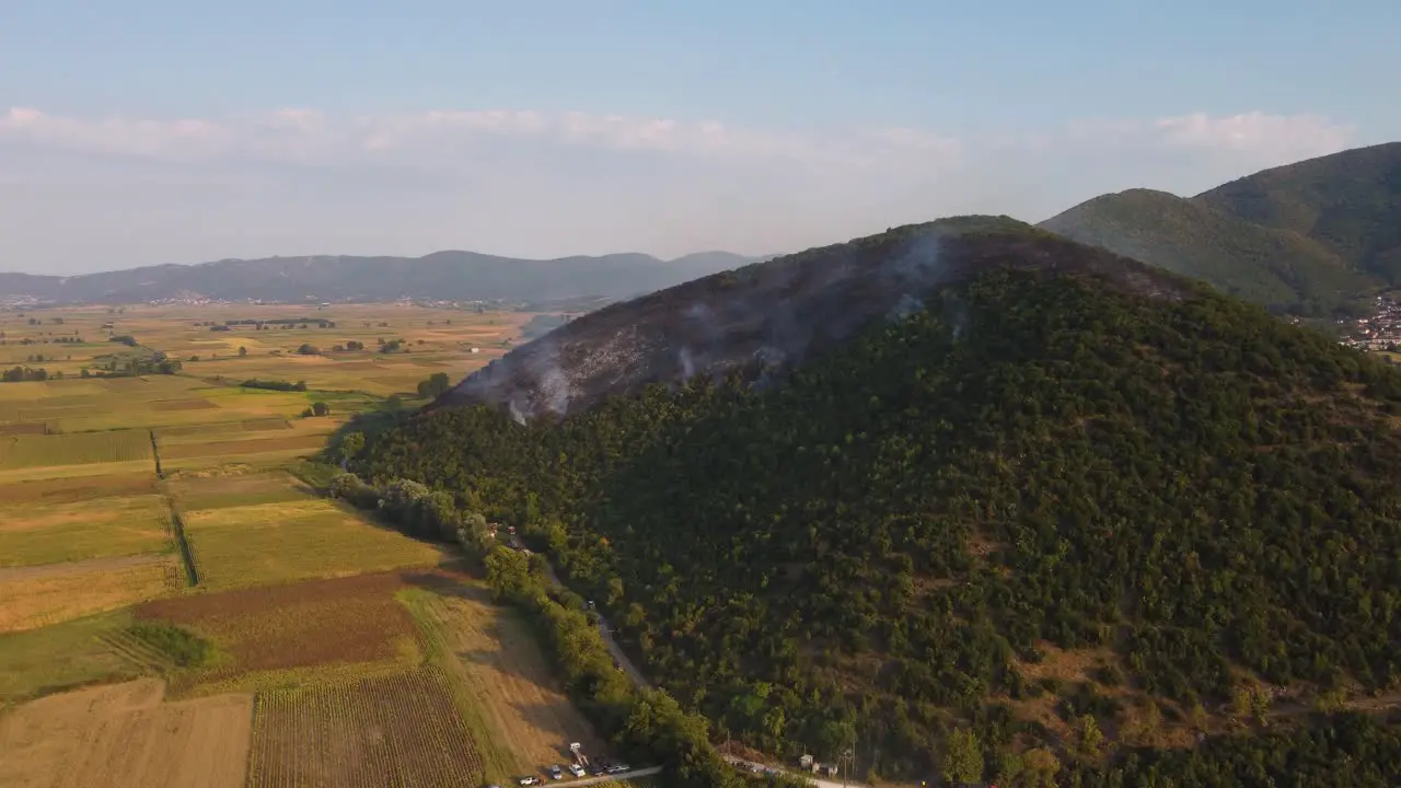 Aerial approaching burning forest above agricultural fields