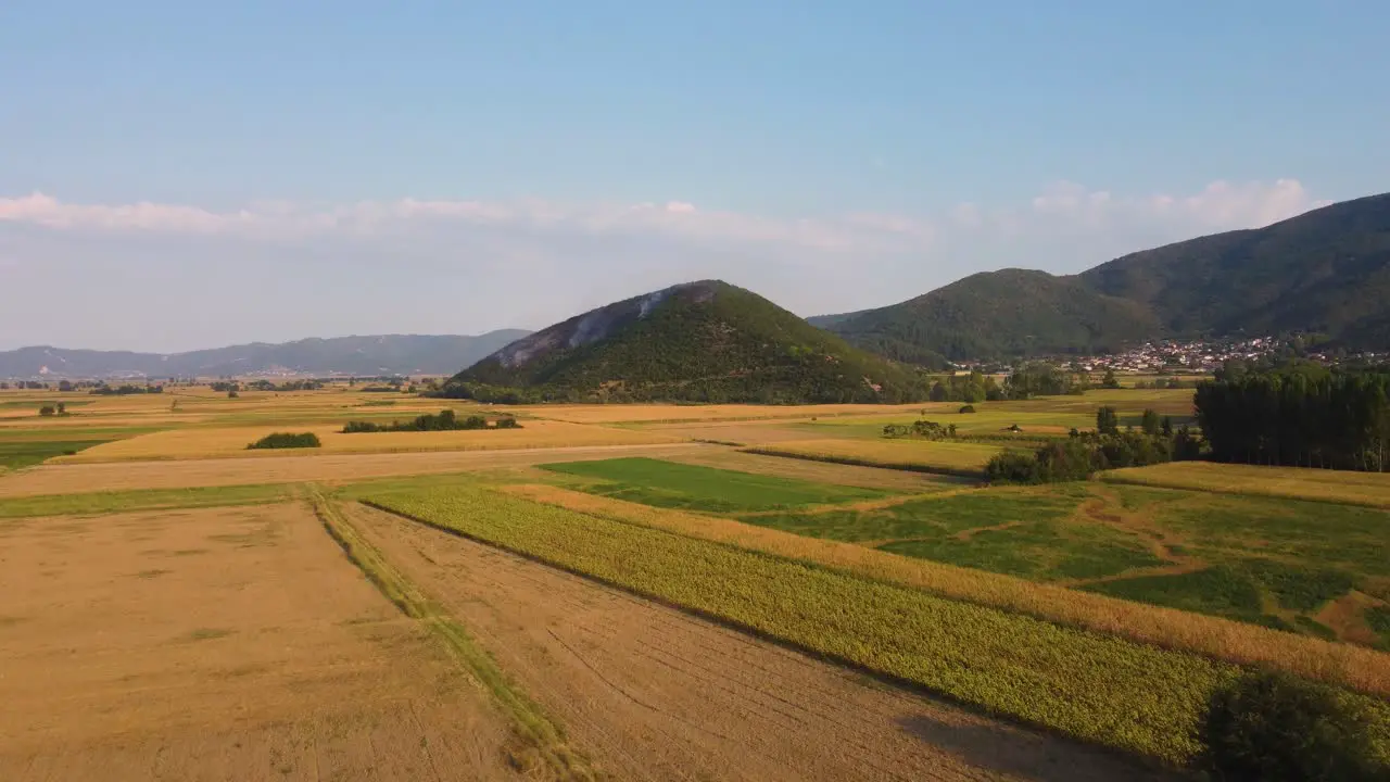 Aerial establishing of wildfire on a hill above agricultural fields in Greece