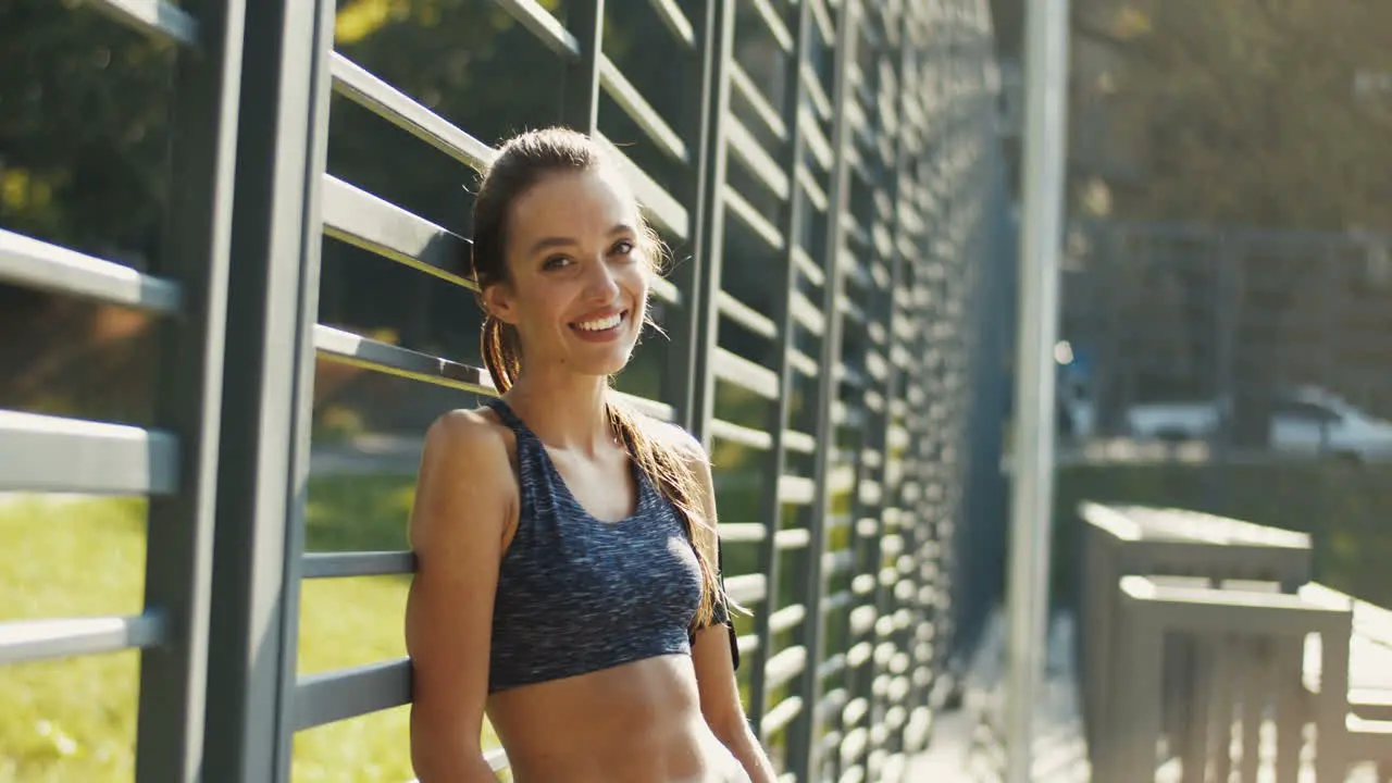 Portrait Of A Cheerful Sporty Woman With Airpods Smiling At The Camera After Workout At Outdoor Court On Sunny Day 1