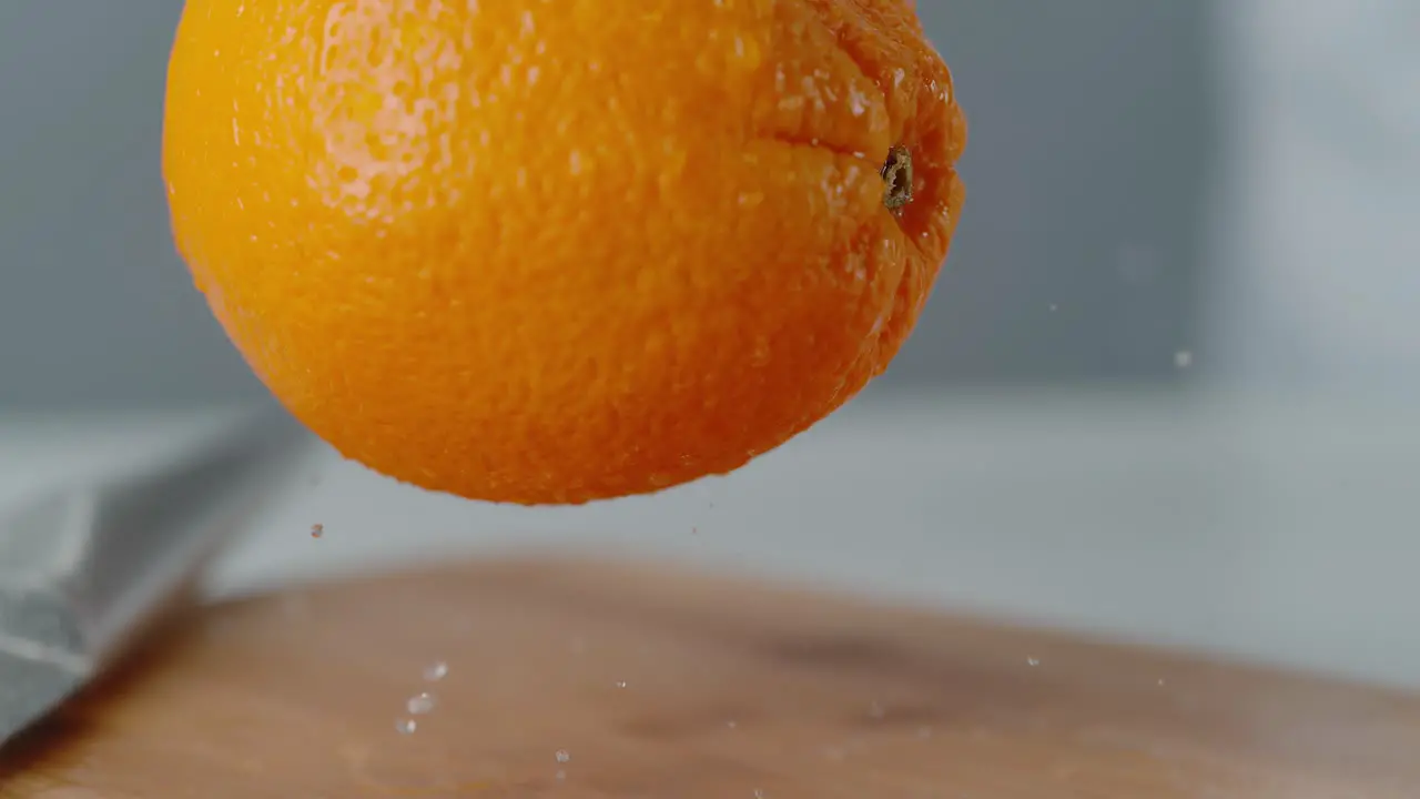 Orange Dropping onto Chopping Board Bouncing with Water Droplets