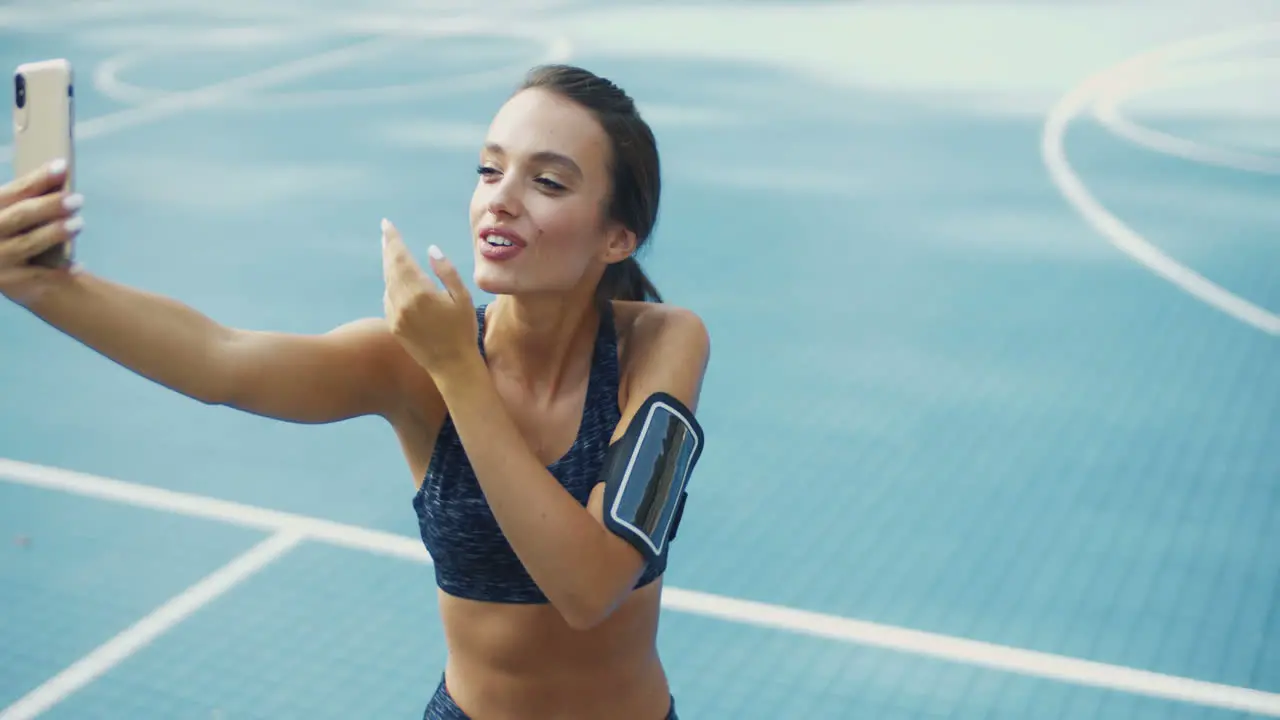 Fitness Woman Blowing Air Kiss And Taking Selfie On Smartphone At Sport Court On A Summer Day