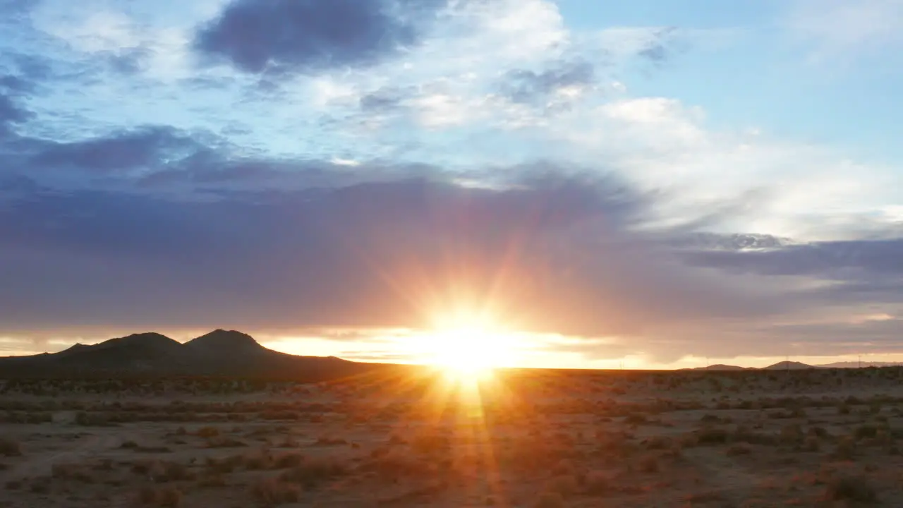 The sun flares over the horizon as dawn comes to the Mojave Desert's arid terrain aerial sliding view