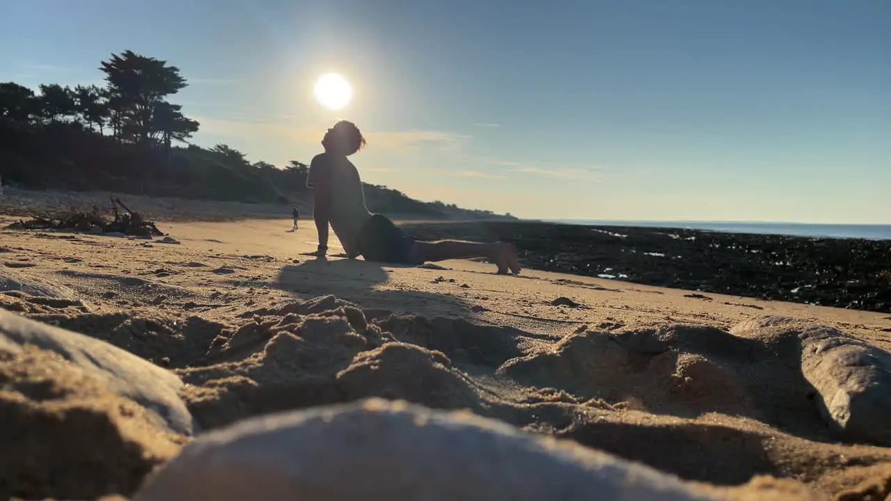 Close up of guy practicing yoga on a beach under sunshine