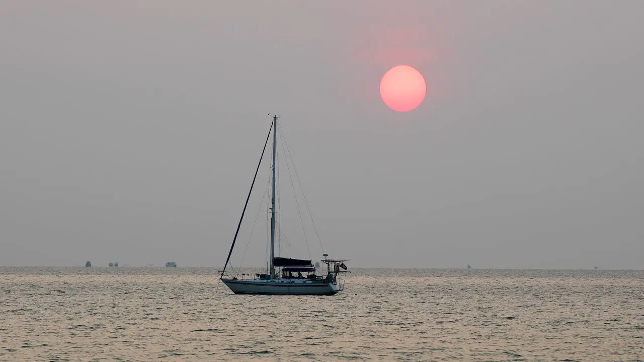 Beautiful Large Sun Over a Yacht on the Horizon During a Sunset in Bangsaray near Pattaya in Thailand