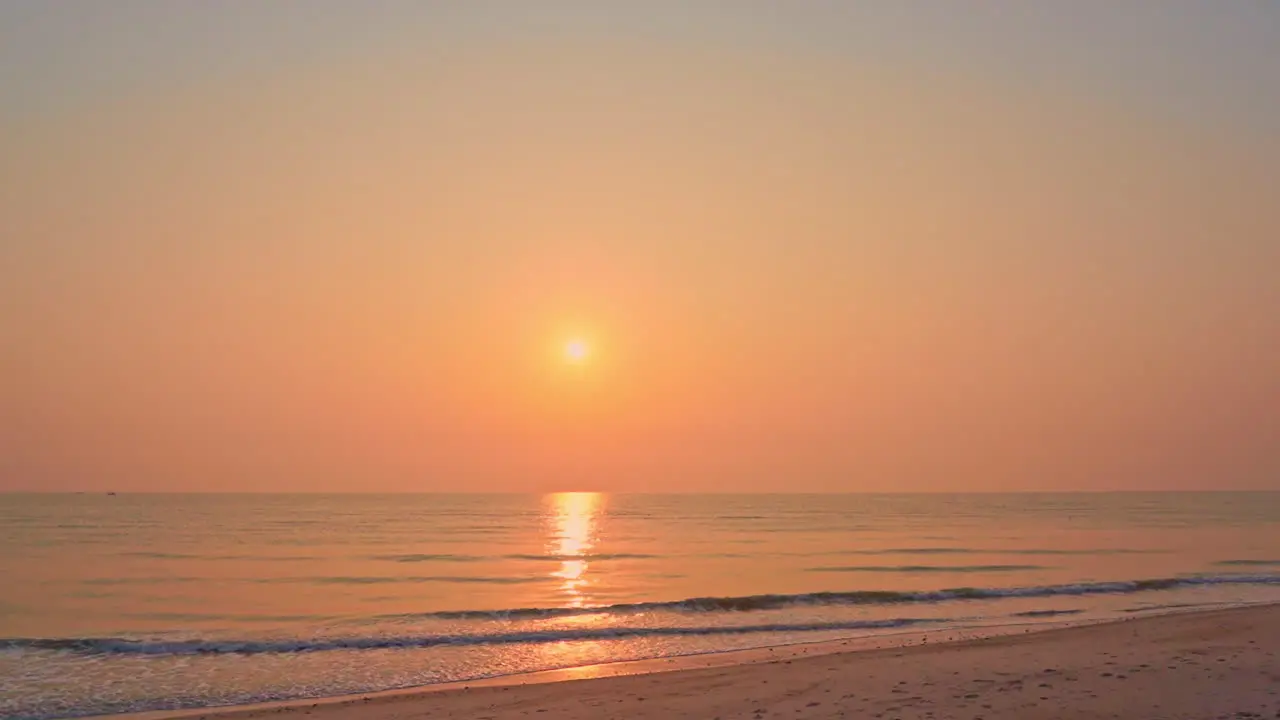 Amazing golden seaside sunset waves slowly rolling towards the sandy beach in Bali camera pans left