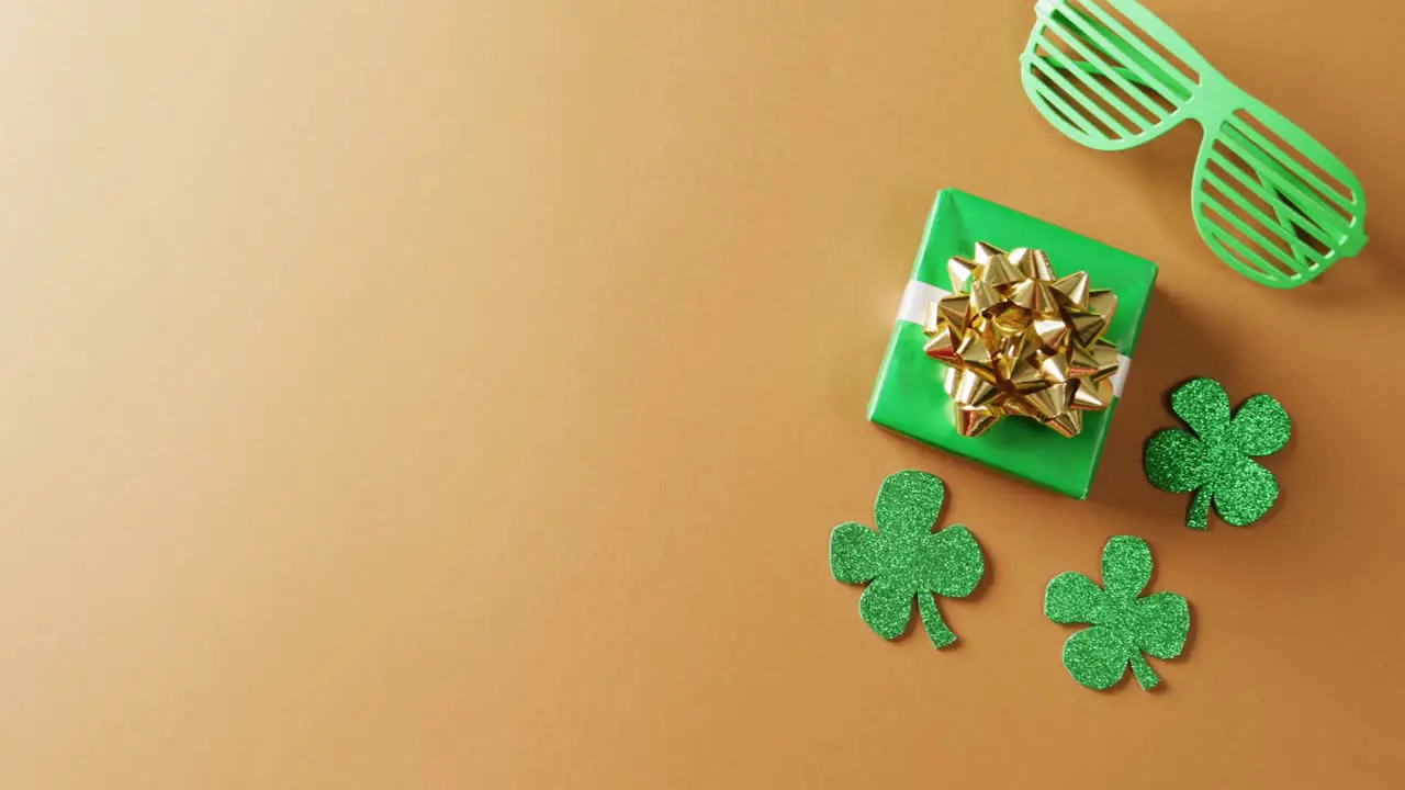 Video of saint patricks day green shamrock present and glasses with copy space on orange background