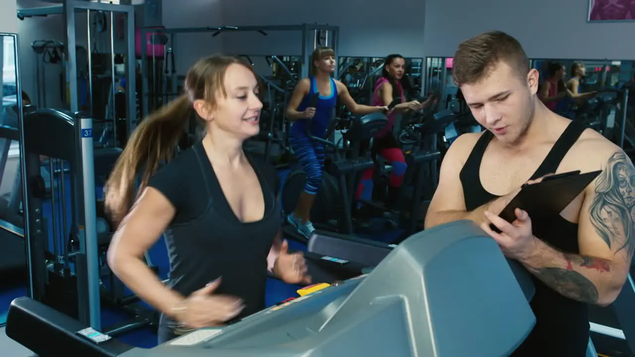 A woman trains in the gym with a trainer