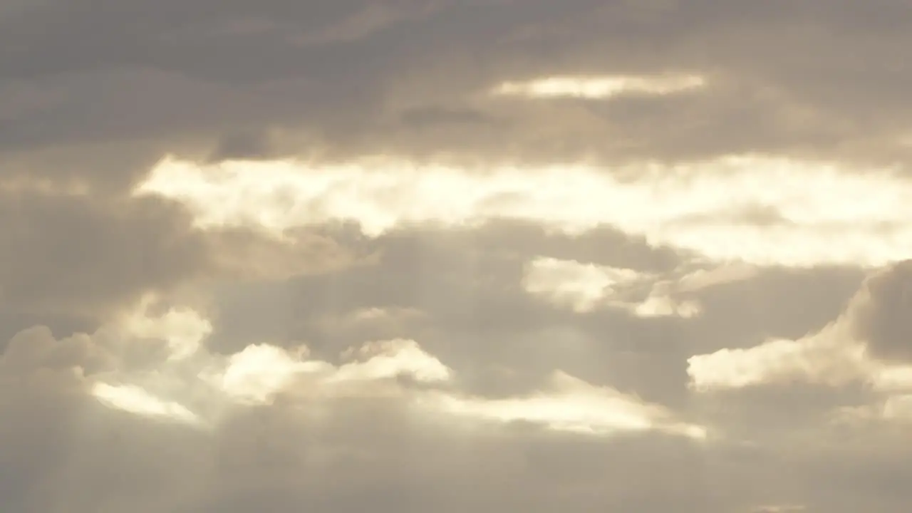 A pan down shot of sun rays coming through the clouds descending above a tropical rainforest during sunset