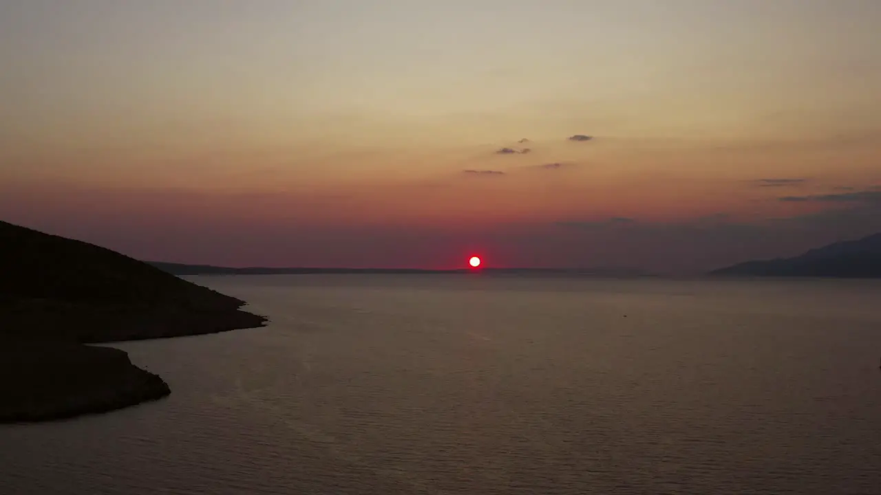 Left tracking shot of dramatic sunset over calm Croatian sea aerial