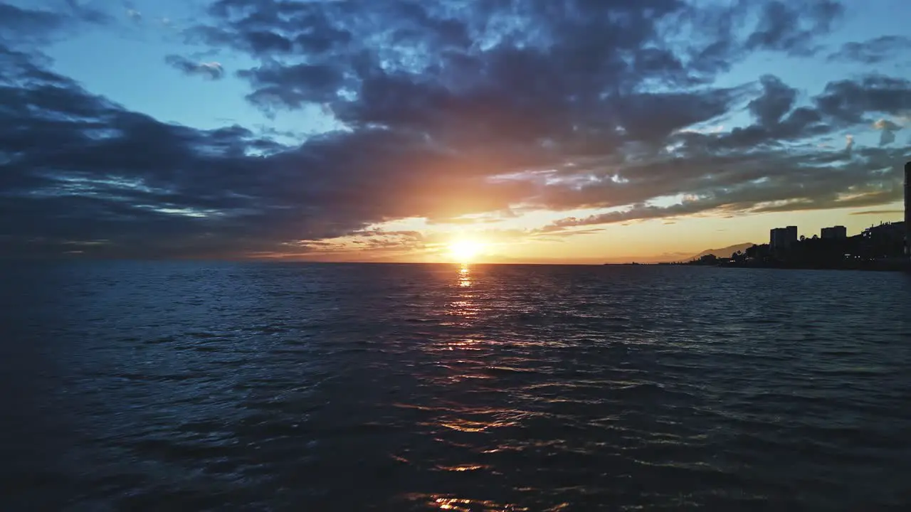 Aerial view of sun under the clouds over the sea moving backwards