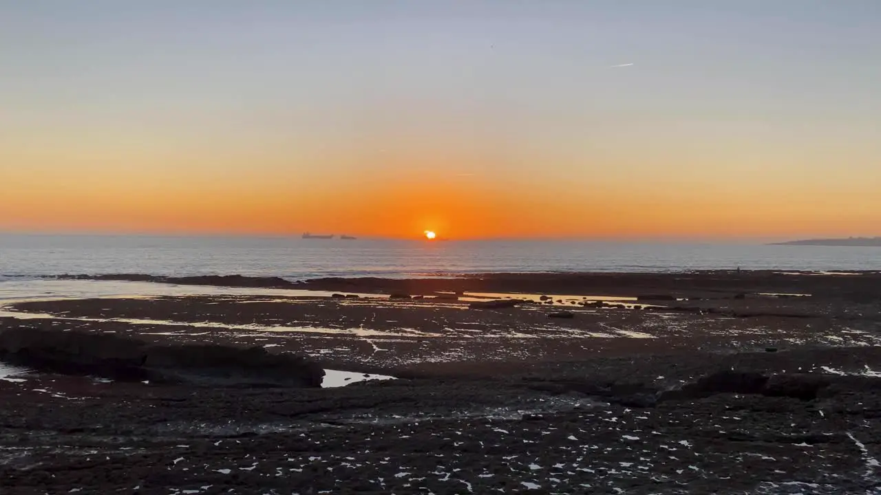 timelapse from the rocks beach for the fascinating landscape sun going down in the middle of the sea