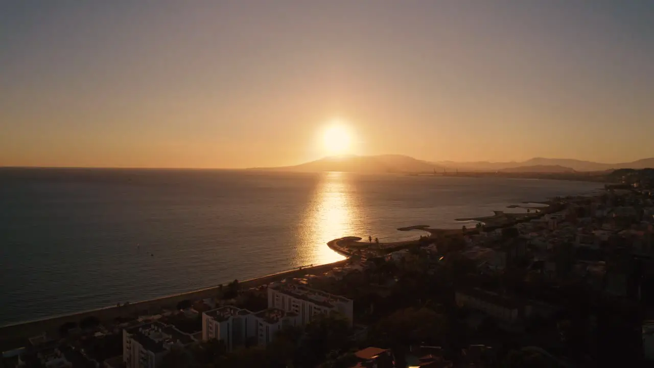 Aerial view of shoreline in Malaga with beautiful golden sunset light hiding behind mountain range