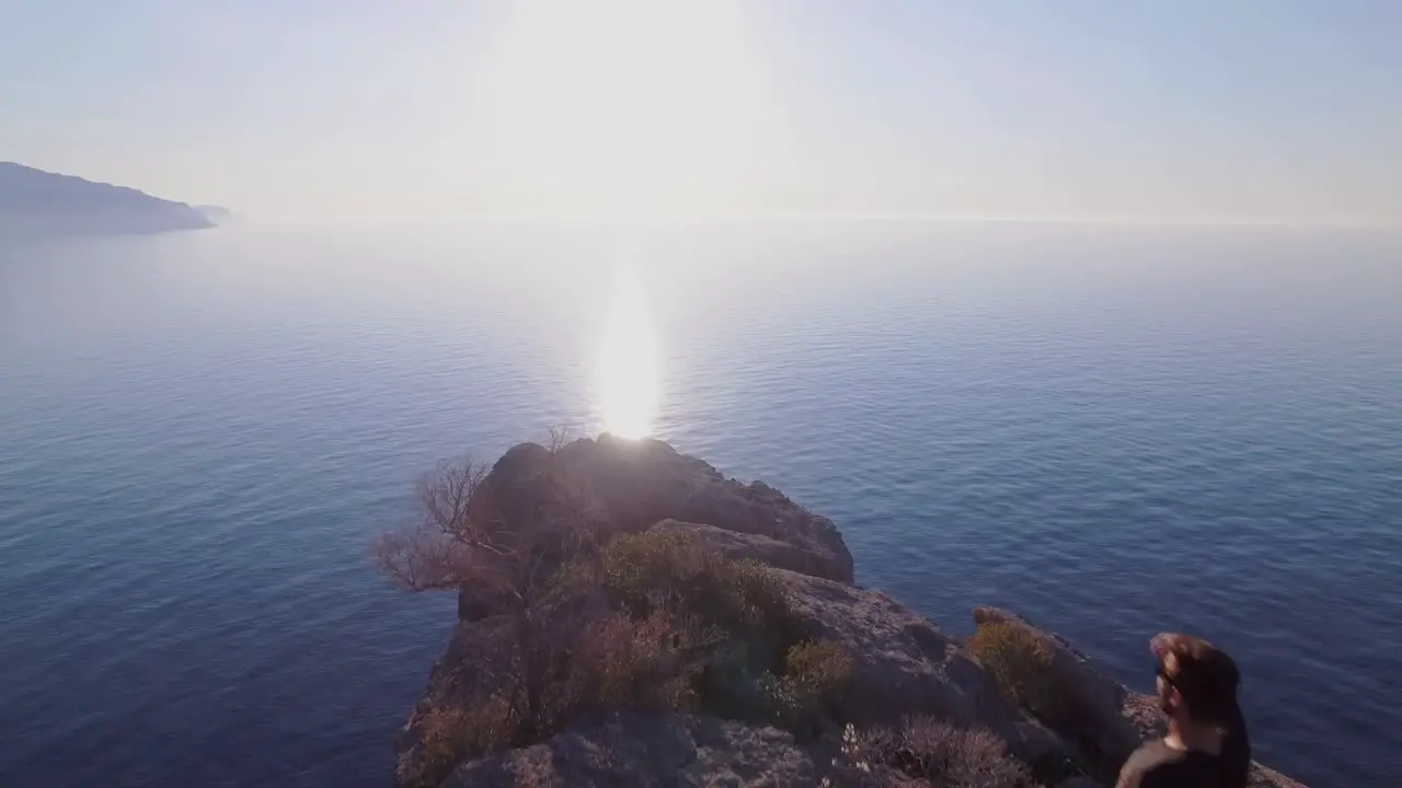 4k drone footage of man climbing on cliff and enjoying the view of the ocean Enjoying life Traveller makes holiday Mallorca Sa Foradada Serra de Tramuntana