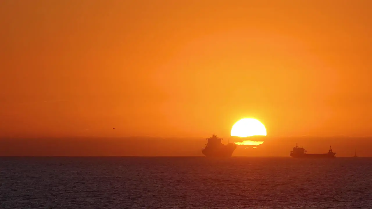 Panorama of two boats drifting at background of sun disk