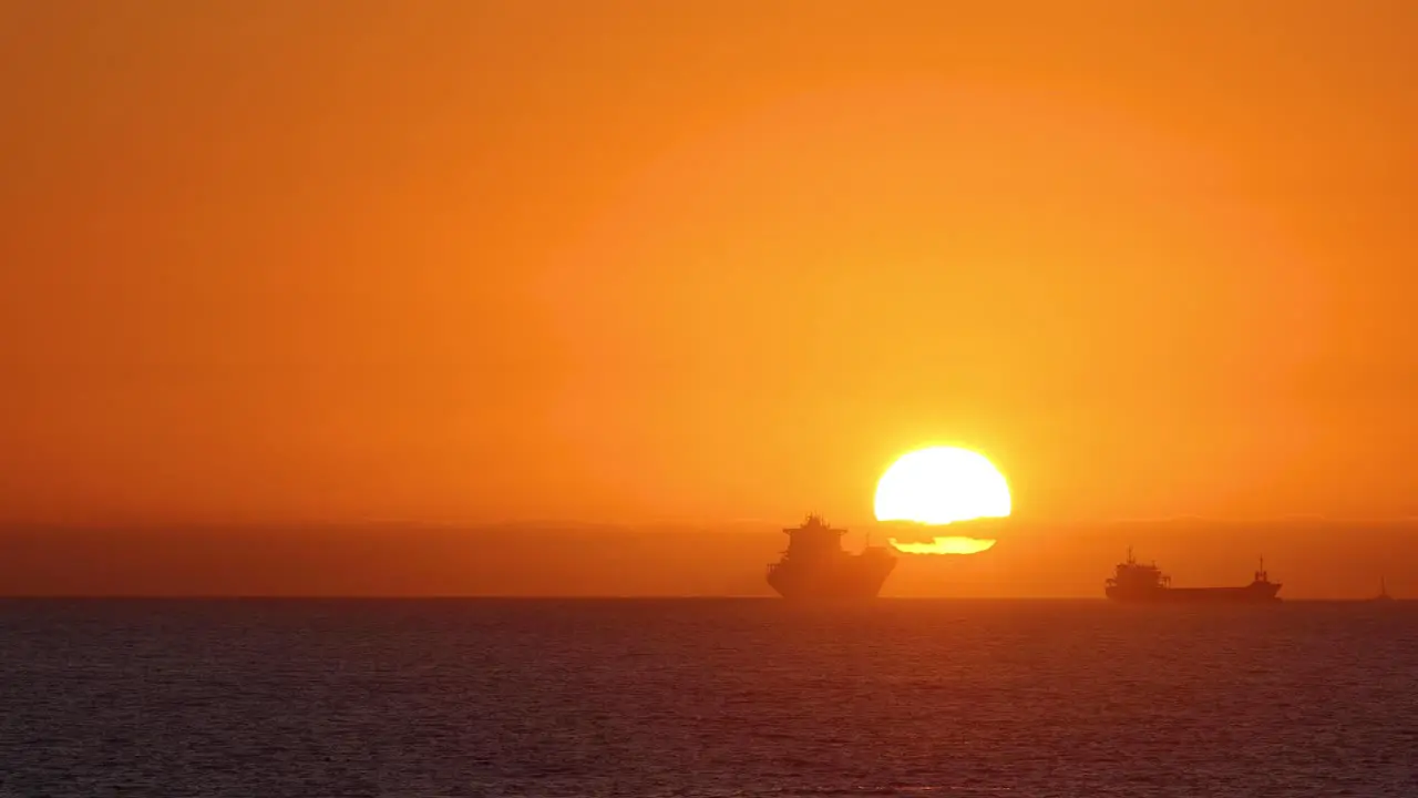 Sailing on a calm sea boats with a golden sunset on the middle