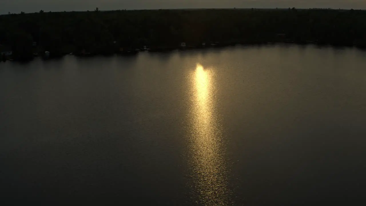 Aerial diffused orange sunlight during sunset reflecting on lake water