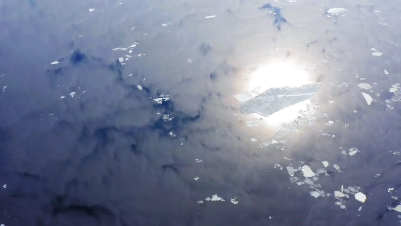 Drone video of ice rafts or floes floating in water blue sky and bright sun reflecting from the surface of the water