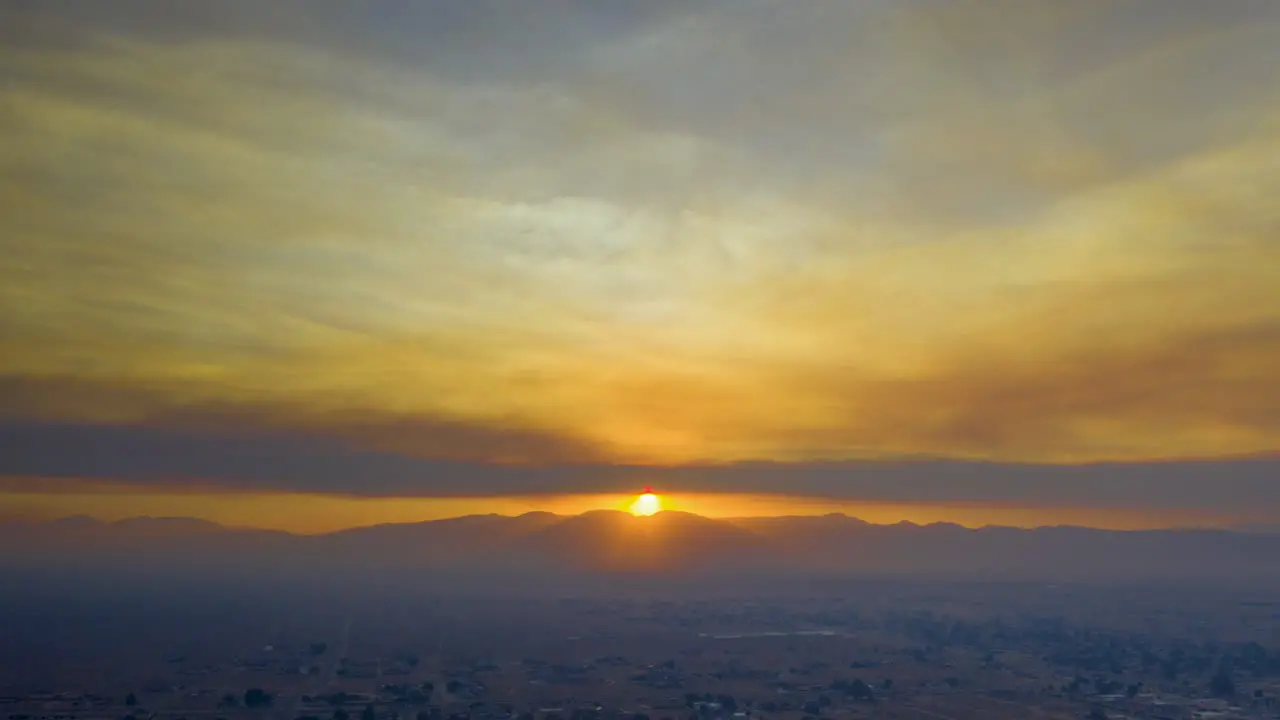 Hazy aerial hyperlapse of the sun setting over the desert landscape covered with smoke from the Lake Fire in southern California