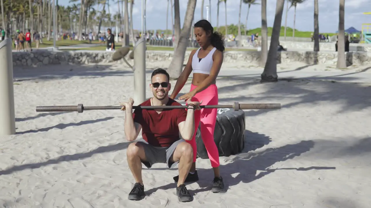 Woman helping man with workout on beach