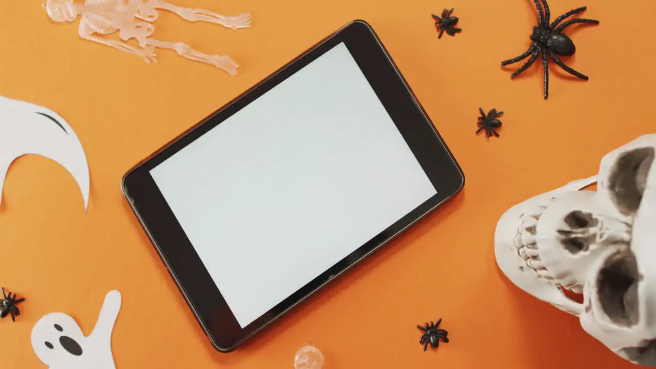 Close up view of halloween toys and digital tablet with copy space against orange background