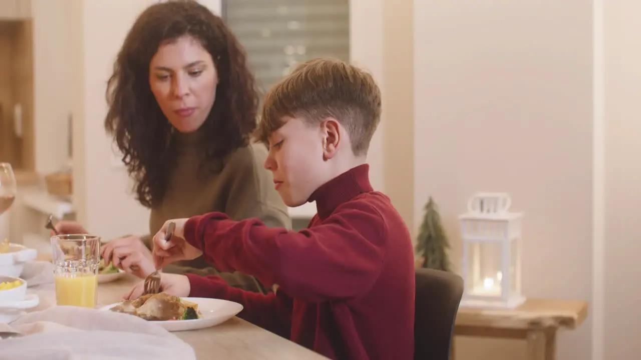 Camera Focuses A Mother And Son Having Dinner At Christmas Sitting At The Table