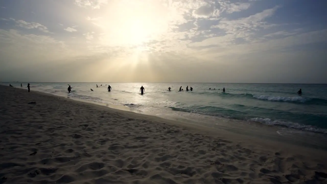 Cuba beach in Varadero during sunset the beach is crowded with people swimming in the sea backlit silhouette