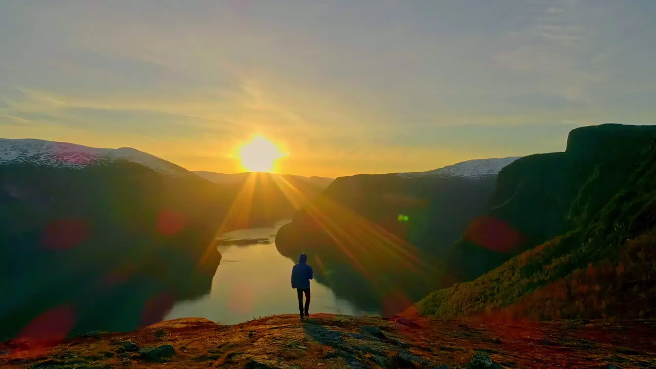 Aerial view of person on peak mountain watching sunset on lake after hike