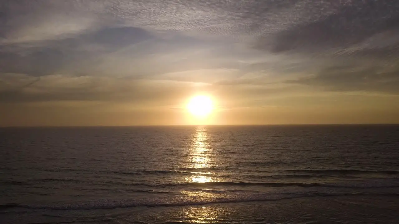 Sunset Seascape Aerial View Flying Over Ocean Sea Water Surface Towards Sun at Sunset Golden Cloudy Sky Calm Waves and Skyline in Horizon