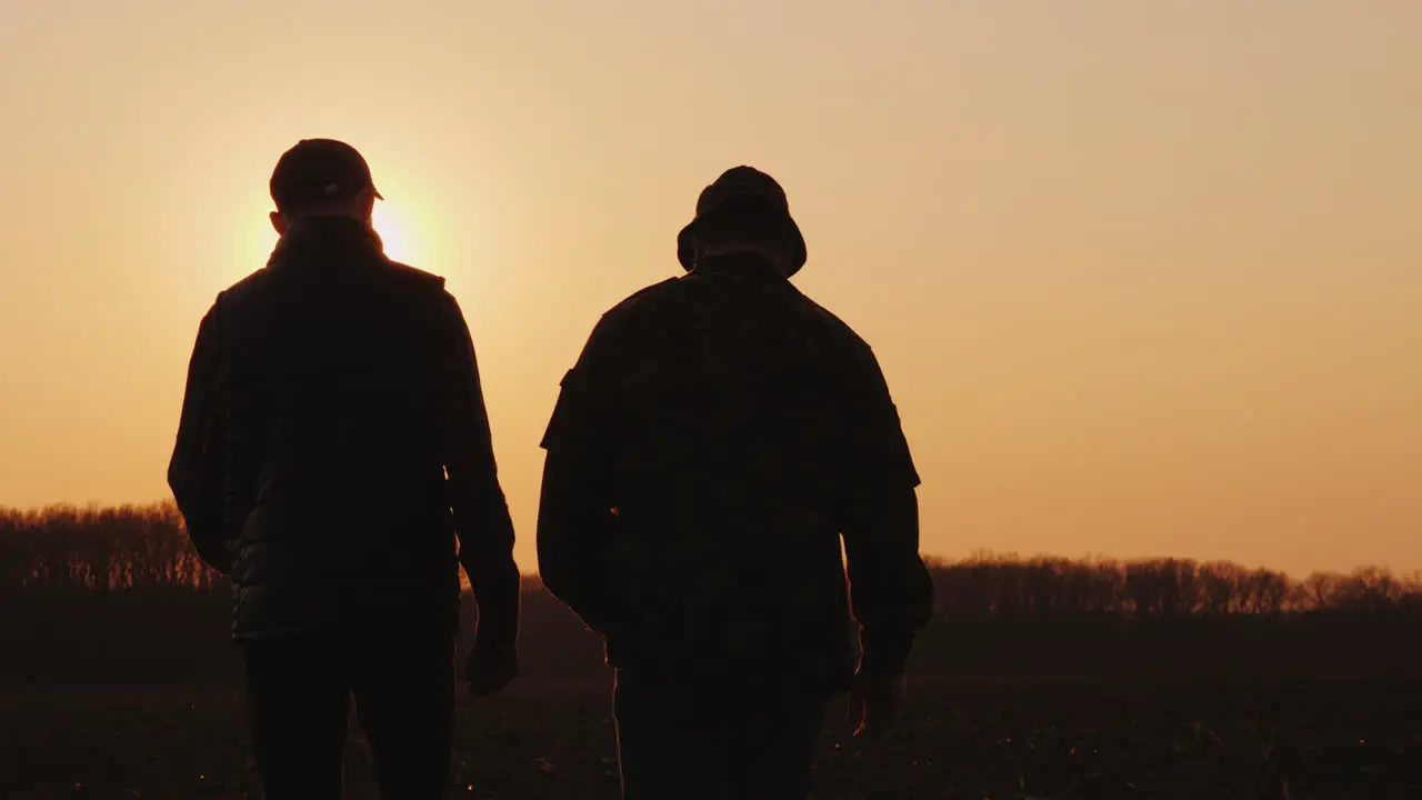 Two Men Farmer Walking Across The Field At Sunset Chatting Startup In Agribusiness