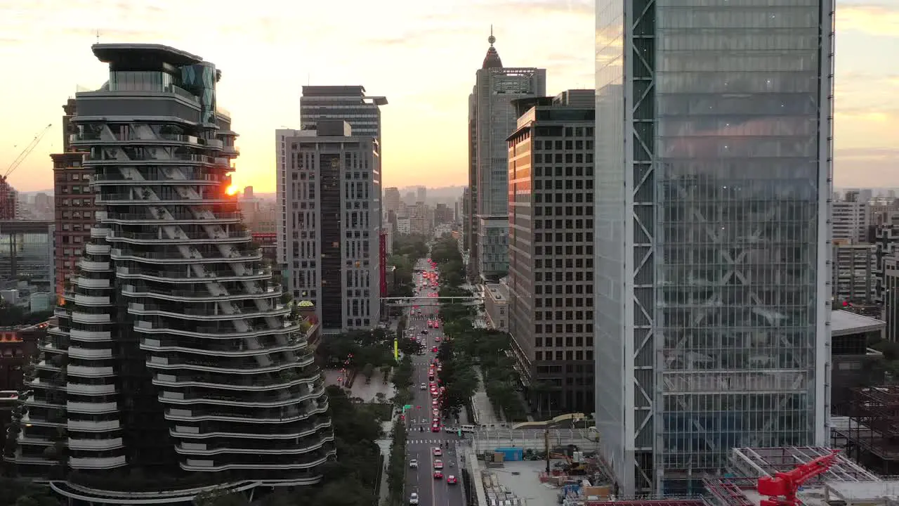 Cinematic aerial pull out shot drone flying above Songgao road with high-rise skyscrapers and apartment complex alongside at sunset in downtown Xinyi district Taipei city Taiwan