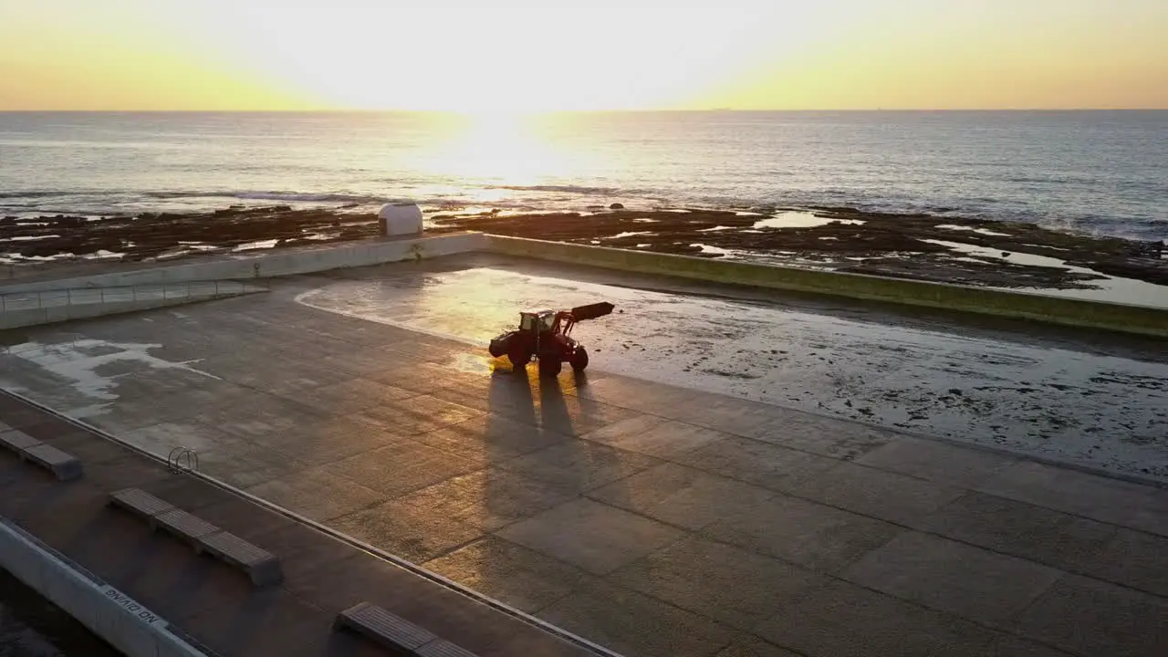 Aerial orbits tractor cleaning pool at Mereweather Beach ocean baths