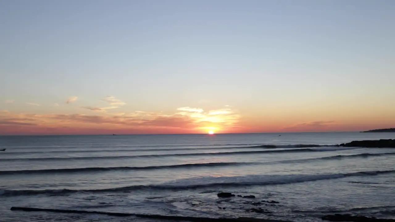 amazing sunset over sea with surfers and boats