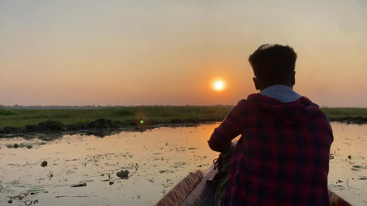 Silhoutte of a lonely man sailing in a boat and looking towards the sun