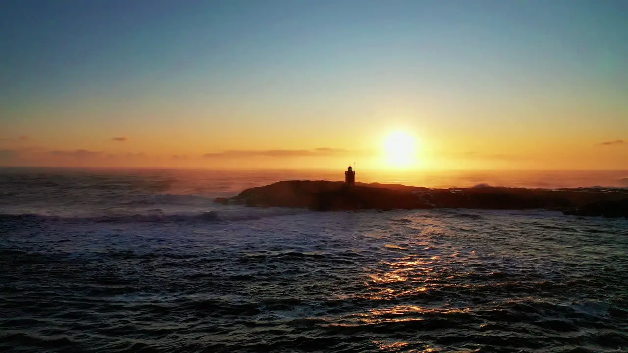 Passing the lighthouse under the beautiful sunset over the ocean in South Iceland aerial