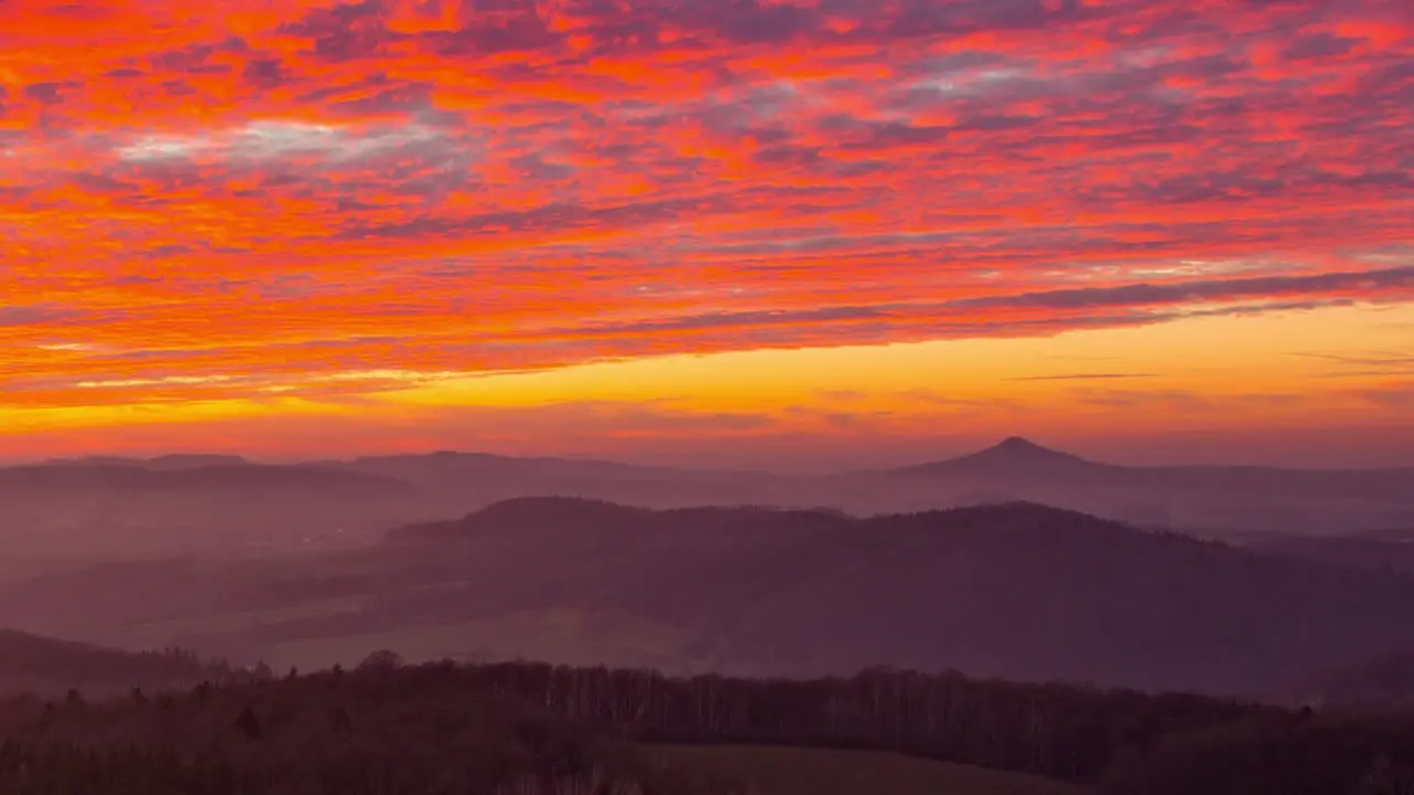 The fiery red orange sky over the old Ostrzyca Proboszczowicka volcano during sunset time lapse