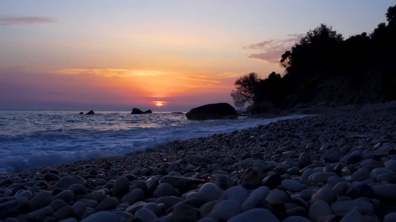 Romantic sunset at beach with sun setting down the clouds of colorful sky reflecting on sea time lapse