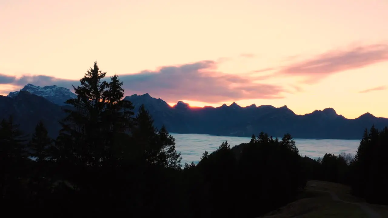 Rising drone shot of a stunning sunset over the cloudy Leitchamm Mountain range