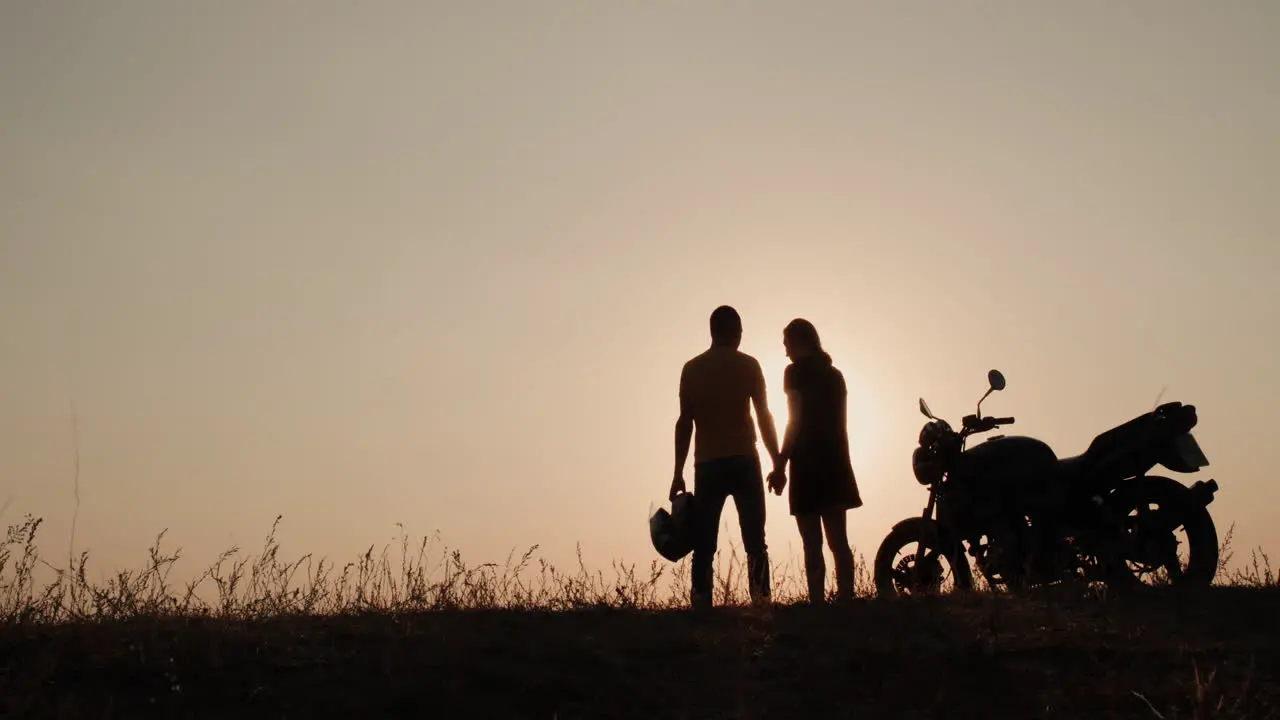 Silhouettes of a young couple near a motorcycle 1