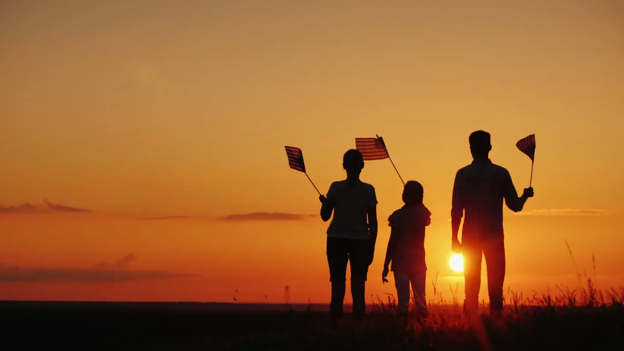 A Group Of People With Flags Of America Looks At The Setting Sun Independence Day In The Usa