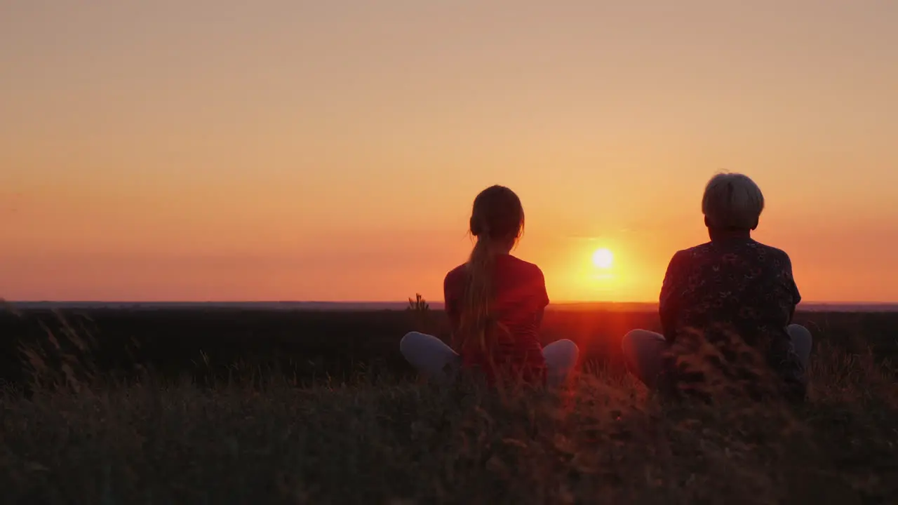 Elderly Woman With Her Granddaughter Admire The Sunset In A Picturesque Place